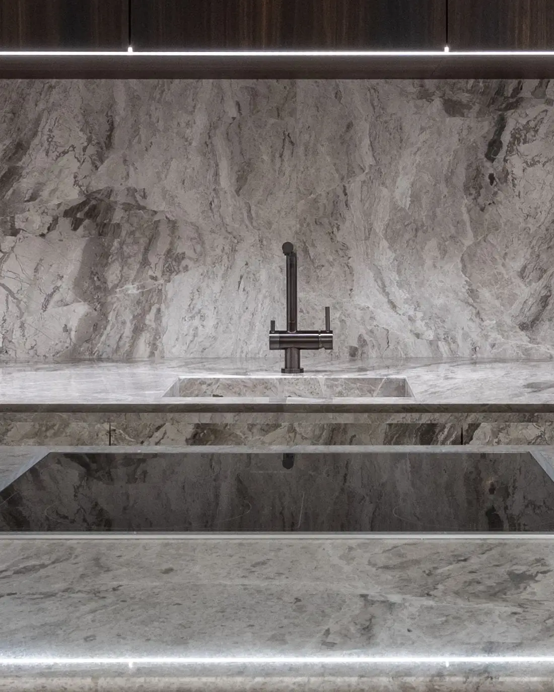 Évier sous plan dans une quartzite grise, robinet noir mat sans marque, crédence dans la même pierre.